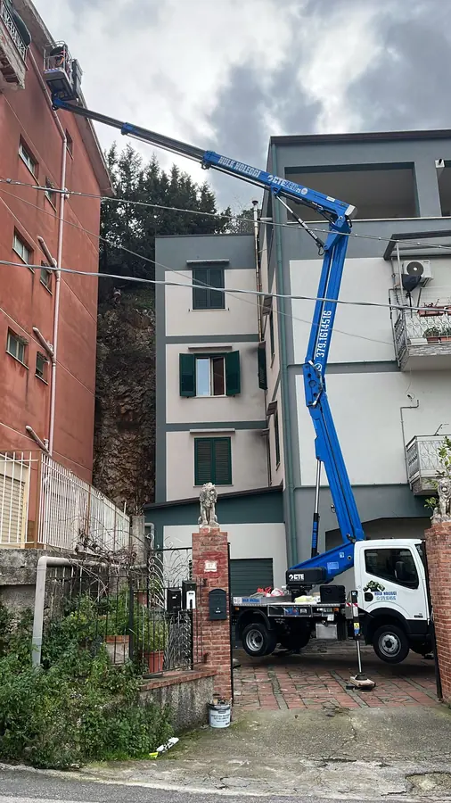 Braccio blu disteso sopra un cancello fino all'ultimo piano di una casa