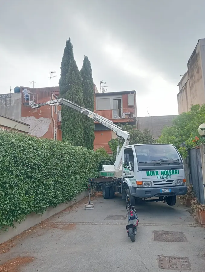 Il mezzo col braccio bianco disteso verso una terrazza, in un cortile con i cipressi