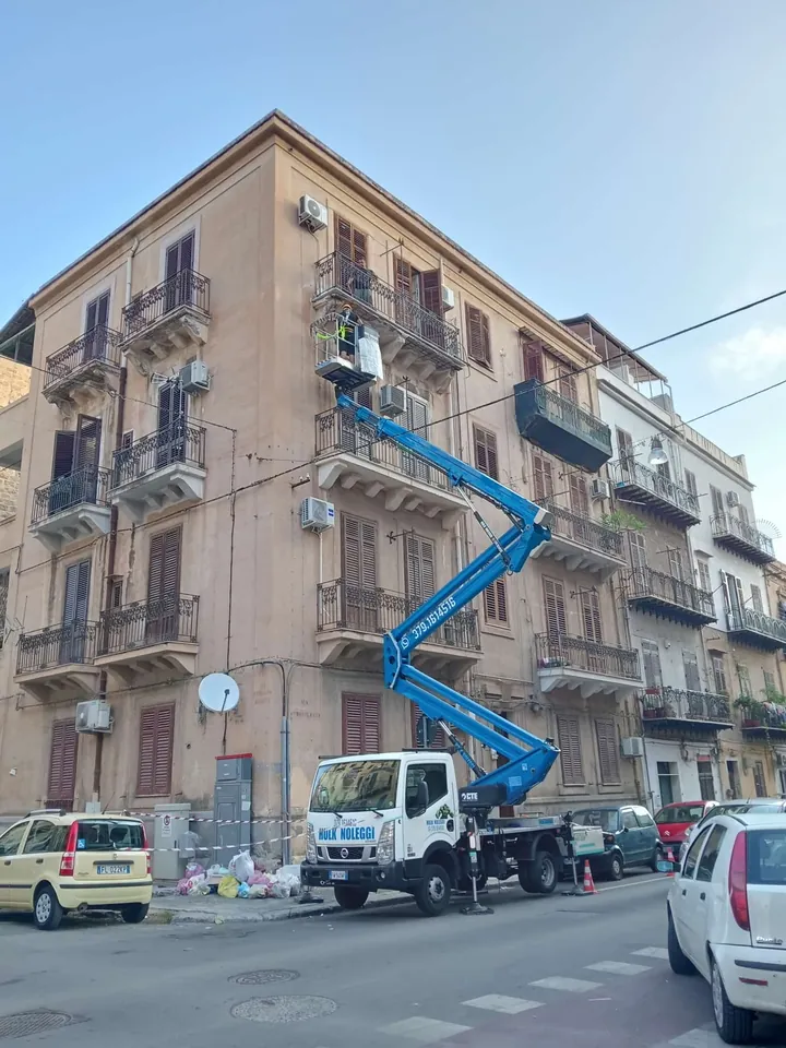 Il braccio blu porta l'operatore al quarto piano di un palazzo d'epoca, in una strada di città