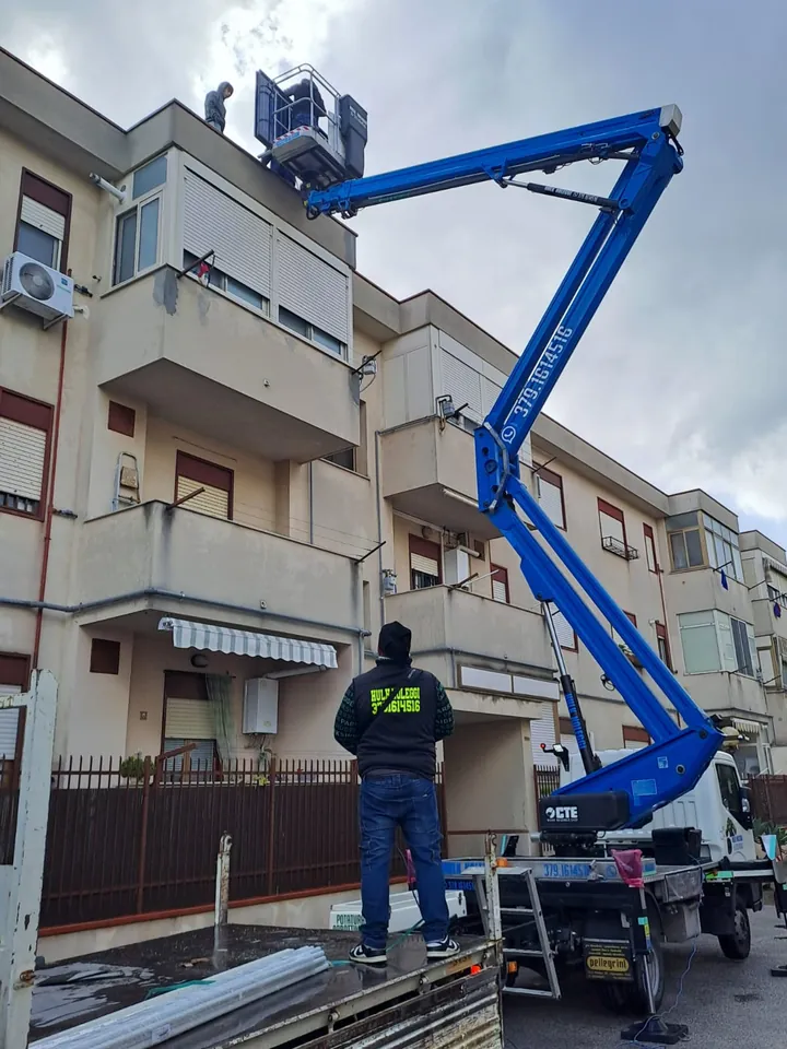 Uomo con la felpa Hulk Noleggi segue il cestello al lavoro sul secondo piano di una palazzina